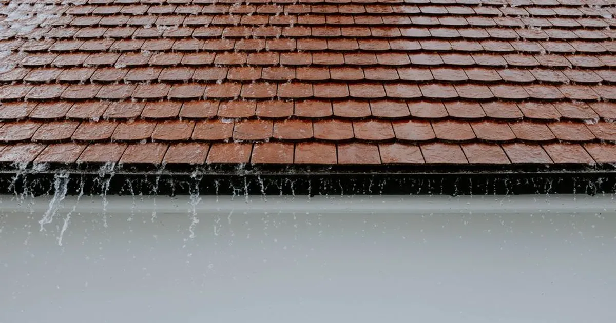 Agua de lluvia cayendo del techo hacia la canaleta de un edificio
